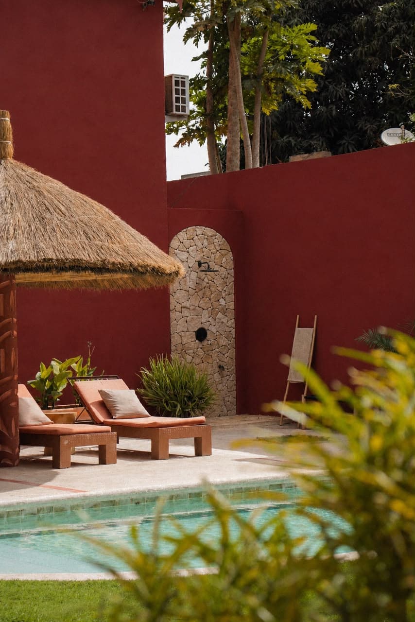 Piscine, transats terracotta et douche extérieure en pierre sous la paillote de l'hôtel Gorée Suites à Saly